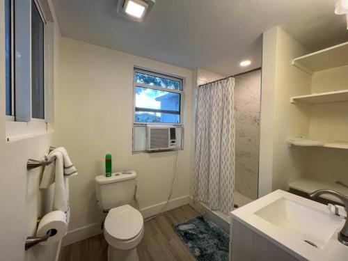 een badkamer met een toilet, een wastafel en een raam bij Stylish Delray Beach house next to pool in Delray Beach