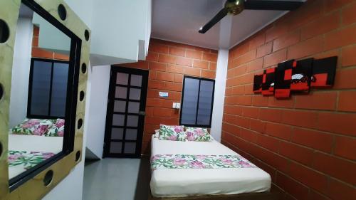 a room with two beds against a brick wall at Hotel Cabañas Mar Caribe in Necoclí