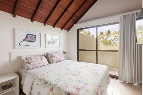 ein Schlafzimmer mit einem Bett und einem großen Fenster in der Unterkunft Bangalô Design Carneiros Beach Resort com serviço in Tamandaré