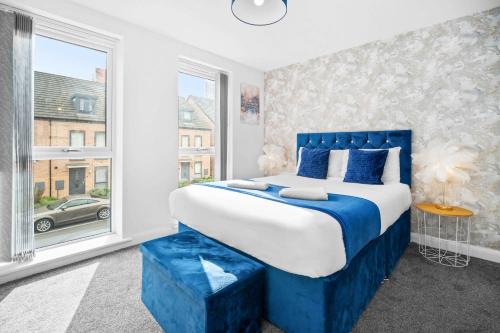 a bedroom with a blue and white bed and a window at Luxury 4 Bed House with En-suite, Games room, BBQ, On-site parking By Azura Nights in Birmingham