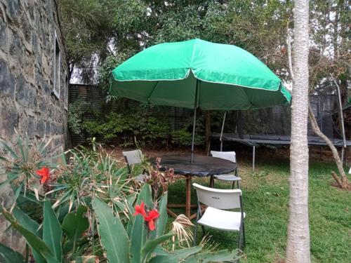 un tavolo e sedie sotto un ombrellone verde di Quiet Place a Kikuyu