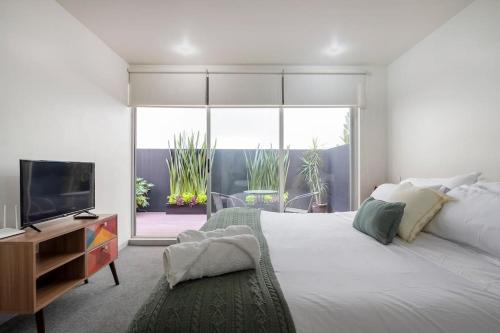 a white bedroom with a large bed and a television at Chic 2BR Condo in Condesa steps from Parque Mexico in Mexico City