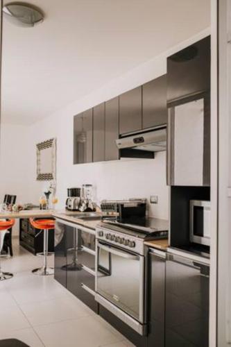 a kitchen with stainless steel appliances and orange chairs at Amplia Casa Moderna c/ Piscina y Lindos Jardines in Trojes de Alonso
