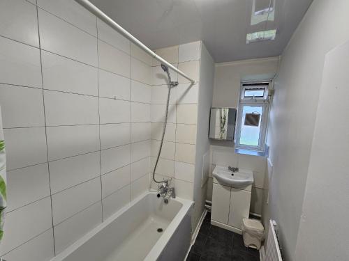 Baño blanco con bañera y lavamanos en Globe Rooms, en Londres
