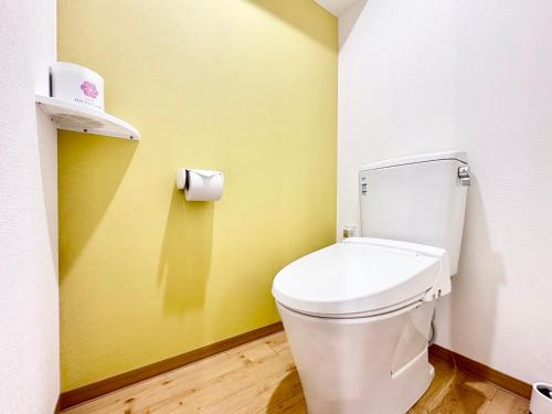 a bathroom with a white toilet and a yellow wall at Hotel Miyakojima in Miyako Island
