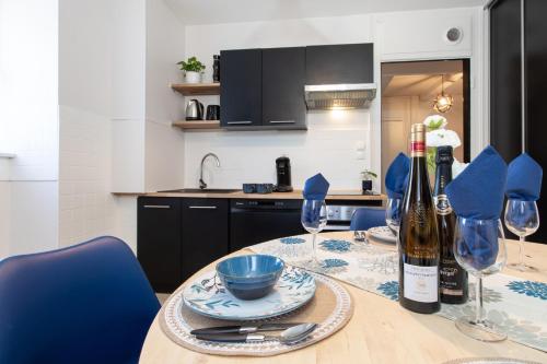 - une cuisine avec une table, des bouteilles de vin et des verres dans l'établissement Refuge Ladhof Odysalis I Chic-Moderne-Proche du centre-ville 3 pieces 2 Chambres, à Colmar