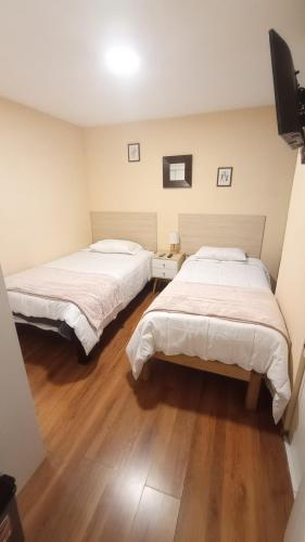two beds in a room with wooden floors at MADA Guest House Puno "Hospedaje" in Puno