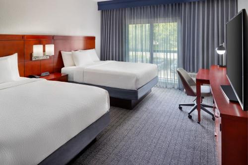 a hotel room with two beds and a desk and a television at Courtyard by Marriott Fort Lauderdale Plantation in Plantation