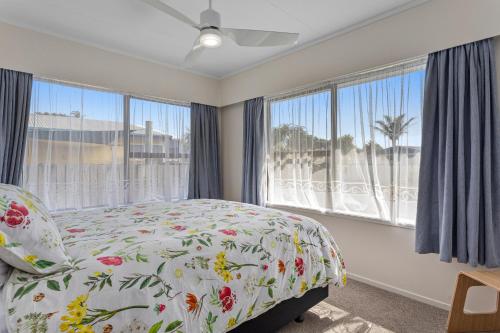 1 dormitorio con 1 cama y ventanas grandes en A Stones Throw - Coastlands Holiday Home, en Whakatane