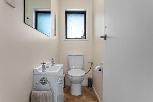 Baño blanco con aseo y lavamanos en A Stones Throw - Coastlands Holiday Home, en Whakatane
