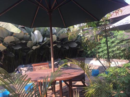 a wooden table with an umbrella on a patio at De Ikut Bojo Homestay in Magelang