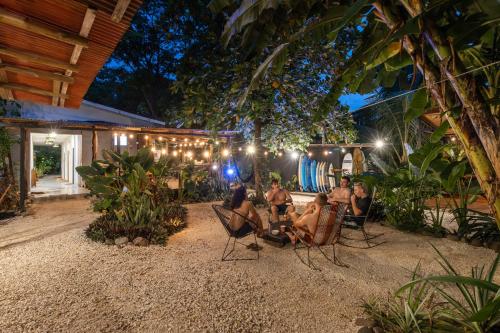a group of people sitting in chairs in a patio at night at Akih Pods Hostel in Santa Teresa Beach