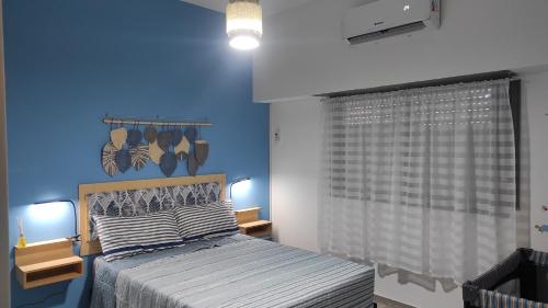 1 dormitorio con cama y pared azul en casa a 20 minutos del aeropuerto de Ezeiza sobre avenida opcional tranfer amplio parque para mascotas rejas y cámaras de seguridad en Monte Grande