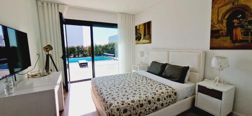 een slaapkamer met een bed en uitzicht op een zwembad bij Lara Sweet Home in Sobral do Parelhão