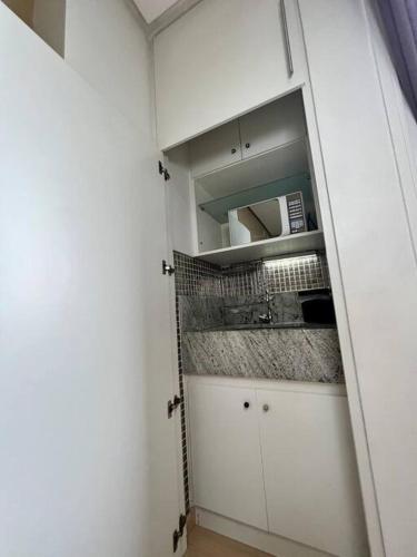 a small kitchen with white cabinets and a microwave at Renoir - Av Barão Homem de Melo nº 4520 - pegar nº do flat no chat após reserva in Belo Horizonte