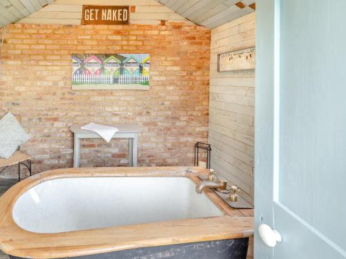 a bath tub in a room with a brick wall at Hallmark Annexe in Tenterden