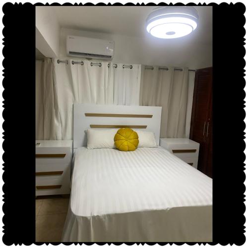 a bedroom with a white bed with a yellow pillow at Apartment in the best of puerto Plata in San Felipe de Puerto Plata