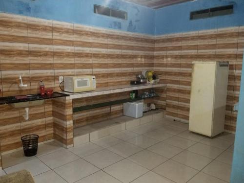 a kitchen with wooden walls and a microwave and a refrigerator at Quarto com ar condicionado, WiFi in Tareco