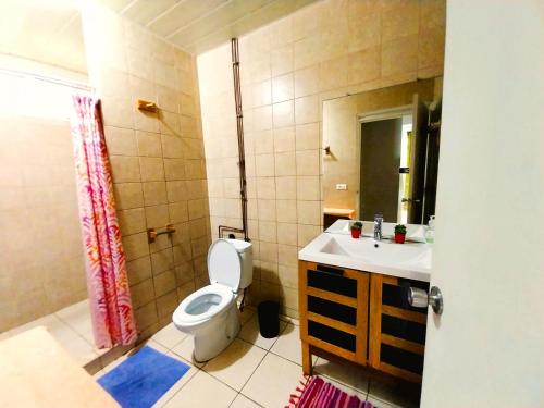 een badkamer met een toilet, een wastafel en een spiegel bij MOOREA - Fare Taina Nui in Haapiti