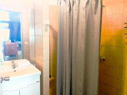 ein Bad mit einem Duschvorhang und einem Waschbecken in der Unterkunft MOOREA - Fare Taina Iti in Haapiti