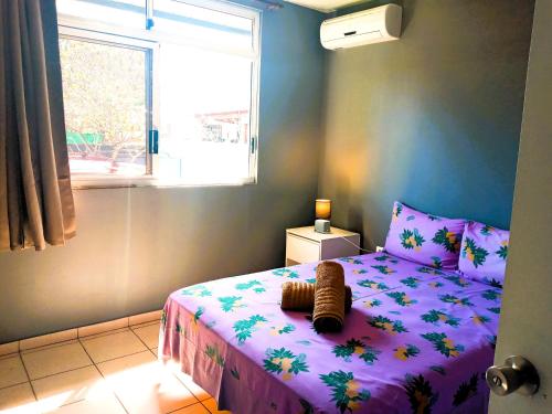 een slaapkamer met een bed met een paars dekbed en een raam bij MOOREA - Fare Taina Iti in Haapiti