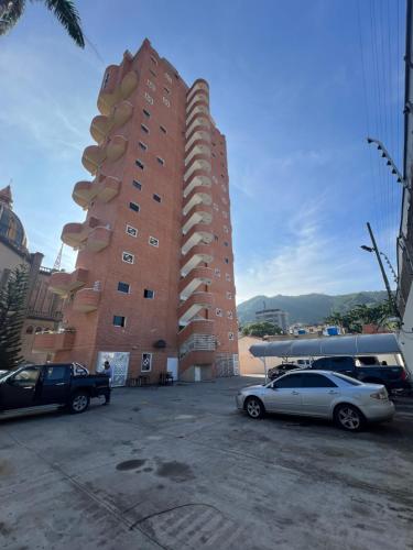 a large red brick building with cars parked in a parking lot at Hospitalidad y confort in Caracas