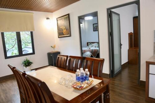 a dining room with a table with bottles and glasses on it at JE T'AIME VILLA - Khu nghỉ dưỡng nhà vườn nằm giữa thiên nhiên bao la hoa cỏ in Bao Loc