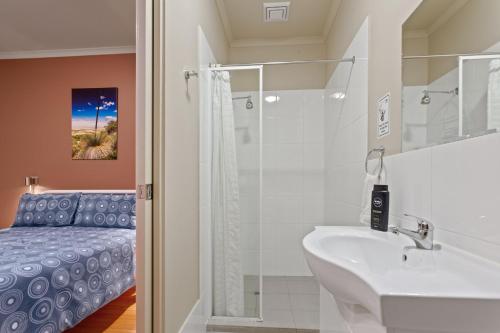 La salle de bains est pourvue d'un lavabo et d'une douche. dans l'établissement Port Lincoln Studio Apartments, à Port Lincoln