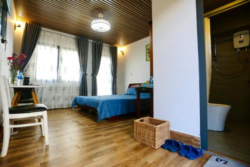 a bedroom with a bed and a table and window at JE T'AIME VILLA - Khu nghỉ dưỡng nhà vườn nằm giữa thiên nhiên bao la hoa cỏ in Bao Loc