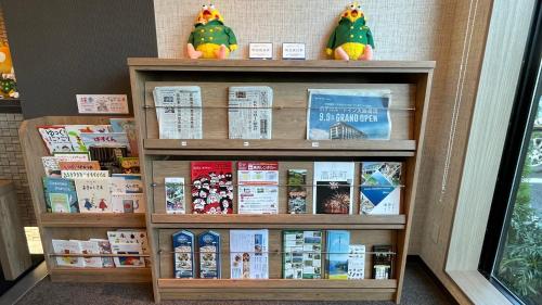 a book shelf with books and stuffed animals on it at Hotel Route Inn Ohi Takahama in Takahama