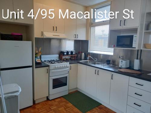 a kitchen with white cabinets and a white stove top oven at At Home Apartments in Sale