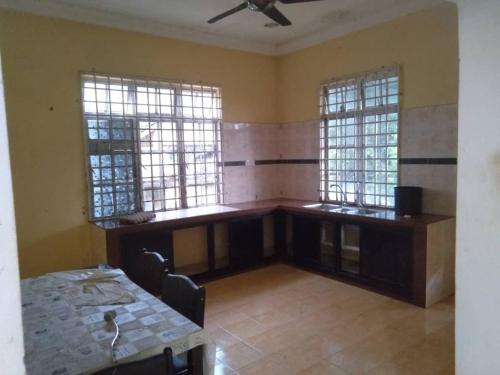 een lege kamer met een tafel en twee ramen bij Familia Homestay Tepi Sawah in Pasir Mas