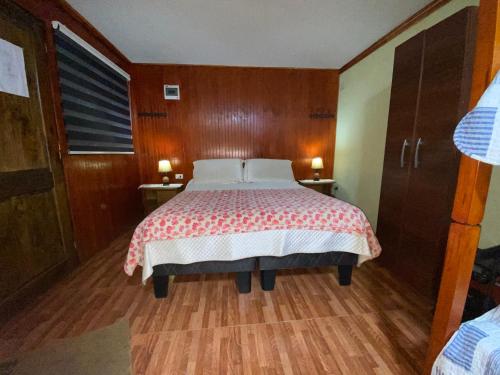 1 dormitorio con 1 cama y 2 mesas con lámparas en Cabañas Dichato Turismo Roma, en Dichato