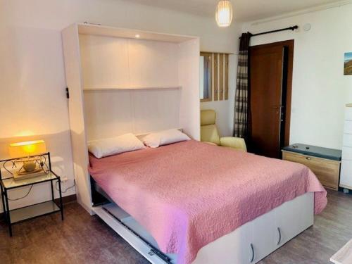 une chambre avec un grand lit avec une couverture rose dans l'établissement Studio Confortable avec Balcon, Parking et WIFI, à Proximité des Thermes et du Centre-Ville - FR-1-703-165, à Amélie-les-Bains-Palalda