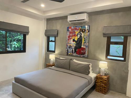 Nathon BayにあるPATAMAAN COTTAGESのベッドルーム1室(ベッド1台付)が備わります。壁には絵画が飾られています。