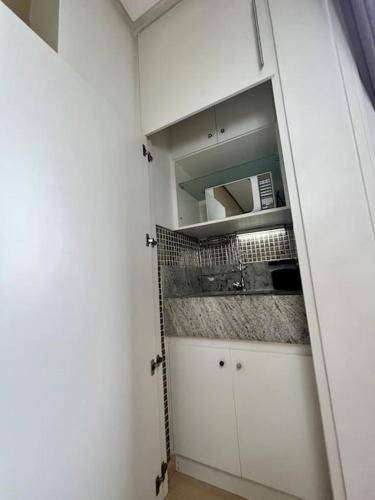 a closet with white cabinets and a microwave at Renoir - Av Barão Homem de Melo nº 4520 - pegar nº do flat no chat após reserva in Belo Horizonte
