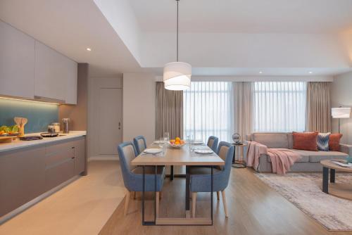 a kitchen and living room with a table and blue chairs at Citadines Roces Quezon City in Manila