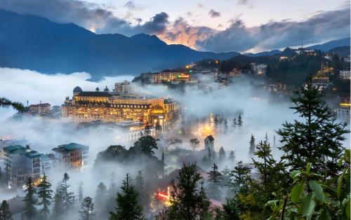 una città nella nebbia di notte con edifici di Central Sapa Charm Hotel a Sa Pa