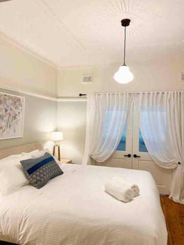 a bedroom with a white bed with white curtains at Katoomba Cottage in Katoomba
