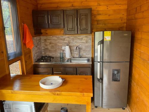 a kitchen with a table and a stainless steel refrigerator at Las Nubes Cabaña in La Mesa