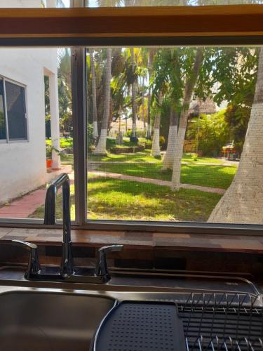 a kitchen sink with a view of a park through a window at ESTUDIO 21 in Barra de Navidad