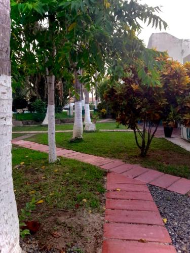 a red brick walkway in a park with trees at ESTUDIO 21 in Barra de Navidad