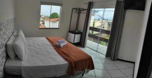 a bedroom with a bed and a large window at Pousada Jardins - Mar Grande in Vera Cruz de Itaparica