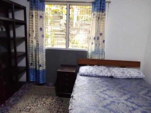 a bedroom with a bed and a window with curtains at Island Home in Honiara