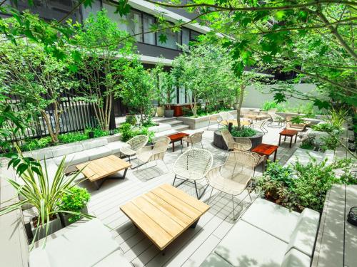 un patio con tavoli, sedie e alberi di The Royal Park Canvas Fukuoka Nakasu a Fukuoka