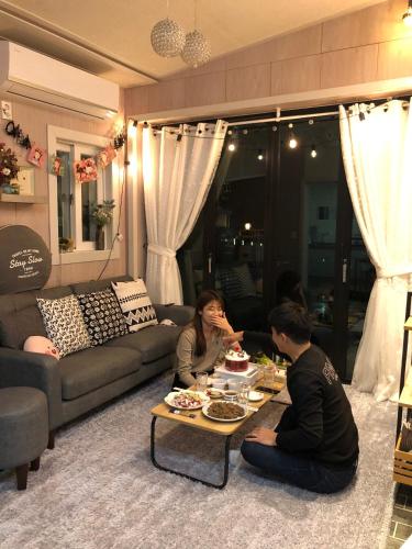 two people sitting around a coffee table in a living room at Us on Earth Guesthouse in Danyang