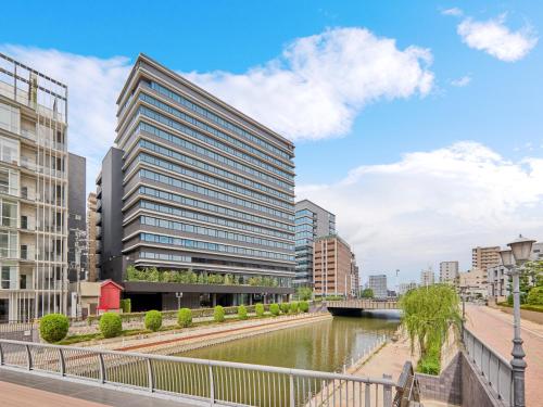 a tall building next to a river with buildings at The Royal Park Canvas Fukuoka Nakasu in Fukuoka