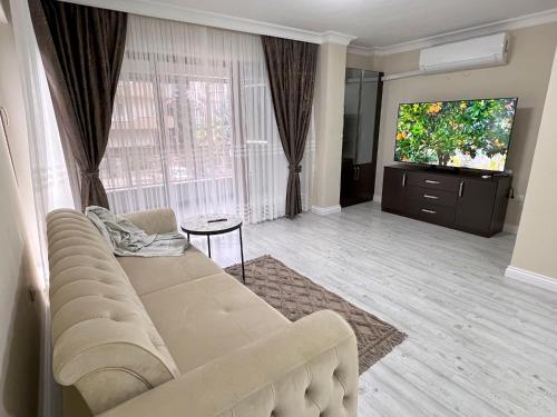 sala de estar con sofá y TV de pantalla plana en NEW Citrus Garden Home Duplex, en Mudanya