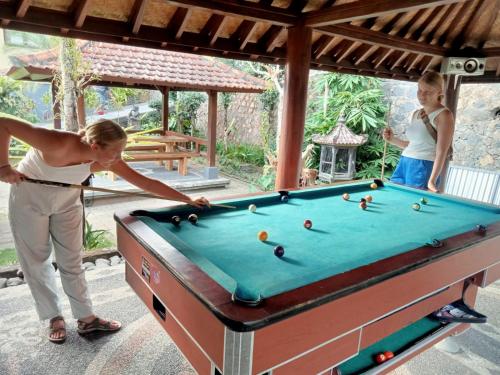 a woman is playing a game of pool at Desa Hostel in Munduk