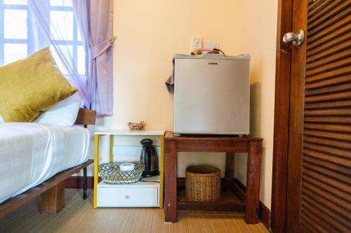a room with a bed and a refrigerator on a table at Mookdaman Bungalow in Ko Yao Noi